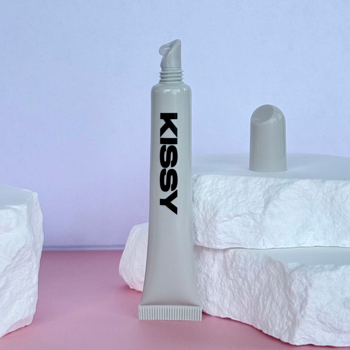 Open tube of Kissy Gloss Natural showing the nude lip gloss applicator in a studio setting